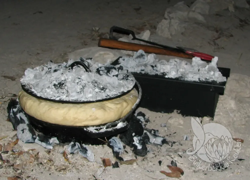 Vers brood dat uit een gietijzeren pot op de kolen rijst