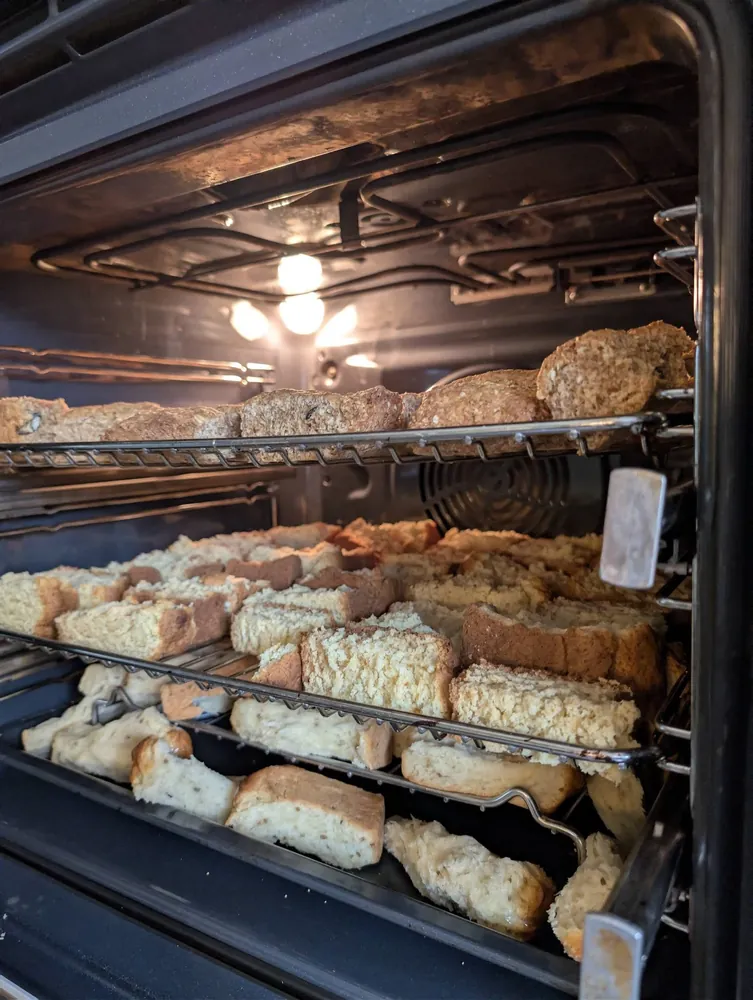 Beskuit cut into pieces, drying across three oven racks